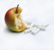Manzana mordisqueada junto a varias pastillas de color blanco