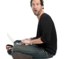 Hombre sorprendido con el ordenador entre sus piernas