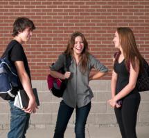 General de dos chicas y un chico, estudiantes que charlan amistosamente en el pasillo del colegio