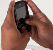 Primer plano de unas manos de color mandando un mensaje a travÃ©s de un mÃ³vil que sostiene entre sus manos