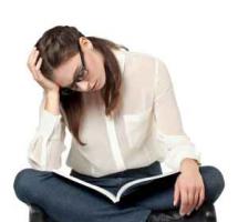 Mujer joven estudia concentrada sentada en el suelo sobre fondo blanco