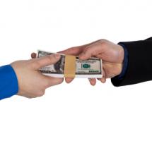 Fajo de billetes de dollar que pasa de una mano a otra sobre fondo blanco