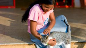 Chica joven acaricia a su gato sentada en el porche de su casa