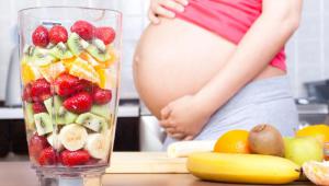 Mujer embarazada con batidora de frutas