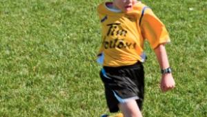 Niño jugando al futbol en un campo de hierva