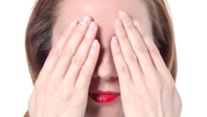 Mujer tapandose los ojos con amabas manos