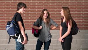 General de dos chicas y un chico, estudiantes que charlan amistosamente en el pasillo del colegio