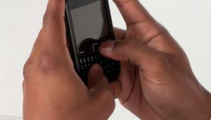 Primer plano de unas manos de color mandando un mensaje a travÃ©s de un mÃ³vil que sostiene entre sus manos