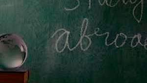 Pizarra escolar con un mensaje escrito en tiza y en ingles que dice" Estudiar fuera"