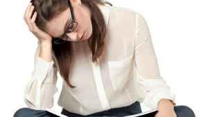 Mujer joven estudia concentrada sentada en el suelo sobre fondo blanco