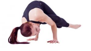 Mujer realizando ejercicios de estiramiento en el suelo. Viste ropa deportiva oscura sobre fondo blanco