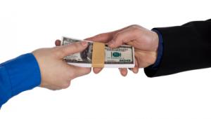 Fajo de billetes de dollar que pasa de una mano a otra sobre fondo blanco