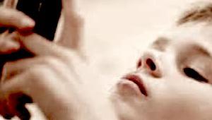 Plano muy cerrado de un niÃ±o jugando con un mÃ³vil tumbado en el suel