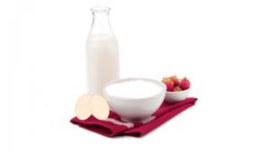 Bodegon con una botella de leche, un par de huevos frescos y un recipiente con fresas, sobre un mantel doblado